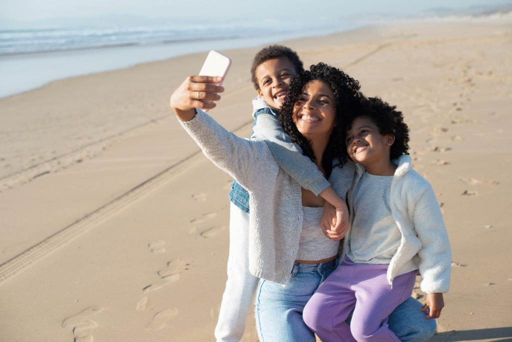 A family taking a selfie together on a sunny beach, smiling and enjoying their vacation.