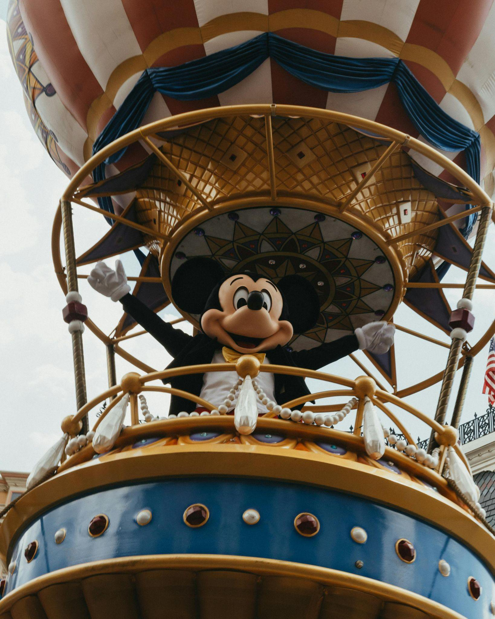 Mickey Mouse waving from a hot air balloon during a parade.